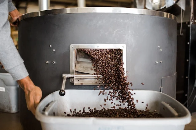 Granos de café saliendo de una cinta transportadora