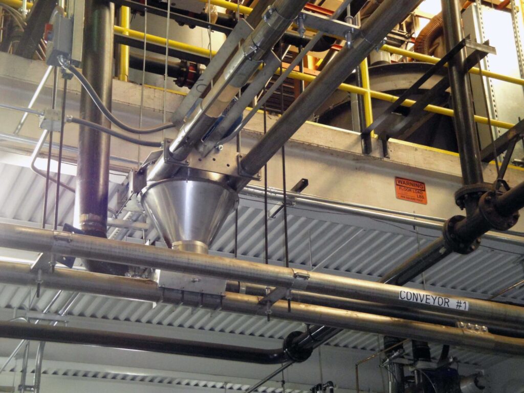 Tubular drag conveyor system in a production facility