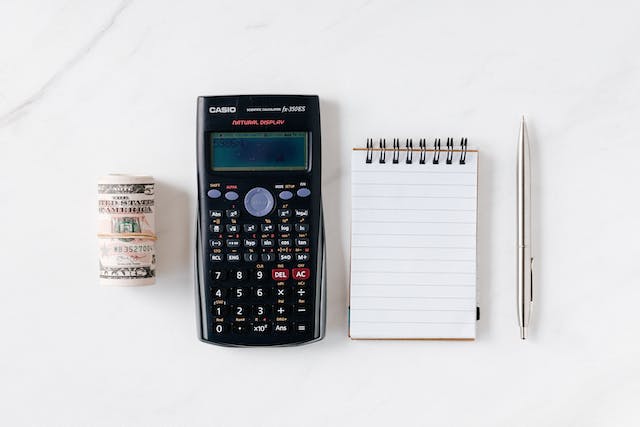 Calculator with paper money and notebook with pen