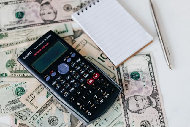 Calculatrice et bloc-notes placés sur la pile de dollars américains