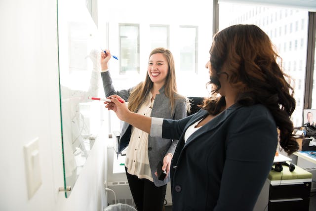 Two women in front of a dry-erase board